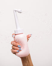 Load image into Gallery viewer, A woman&#39;s hand holds the peri bottle upright while squeezing the bottle and spraying water out of it.
