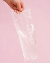 Load image into Gallery viewer, A hand holding one hot and cold pack with clear, eco-friendly gel inside. The product is labeled with the brand name Popped.
