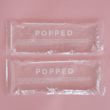 Load image into Gallery viewer, A two-count of hot and cold packs with clear, eco-friendly gel inside. They are both labeled with the brand name Popped, and they are on a pink background.
