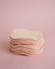 Load image into Gallery viewer, About 20 Popped organic biodegradable absorbent breast pads stacked on each other on a pink background.
