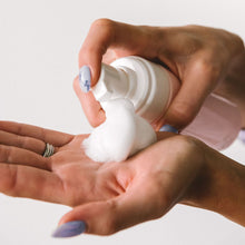 Load image into Gallery viewer, Woman pumping the postpartum witch hazel foam onto her hand. The foam is white and fluffy.