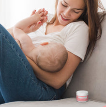 Load image into Gallery viewer, a new mom breastfeeds her newborn with the Popped Organic Nipple Balm next to her
