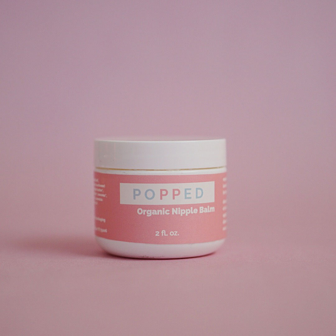 White cylindrical jar with pink label that reads: “Popped Organic Nipple Balm, 2 fl. oz.”