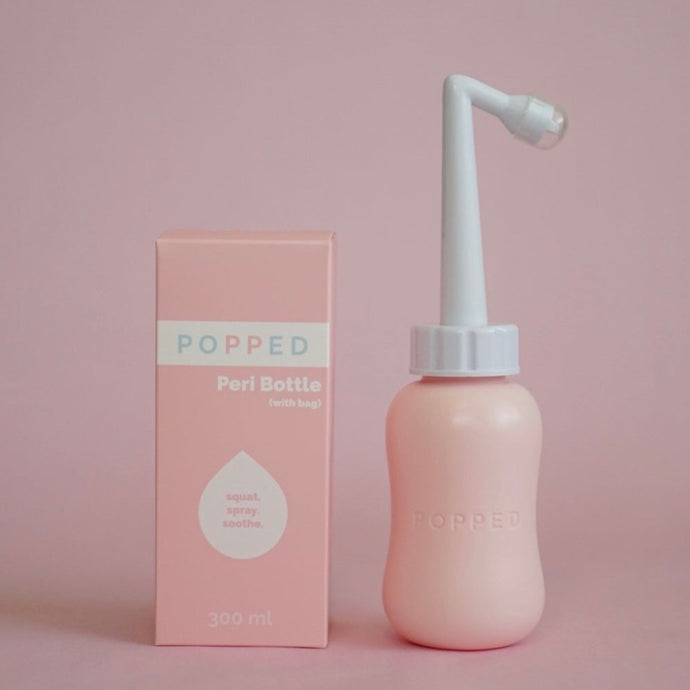 A pink bottle with a long white angled nozzle (with cap) at the top is pictured next to the packaging, which reads, 
