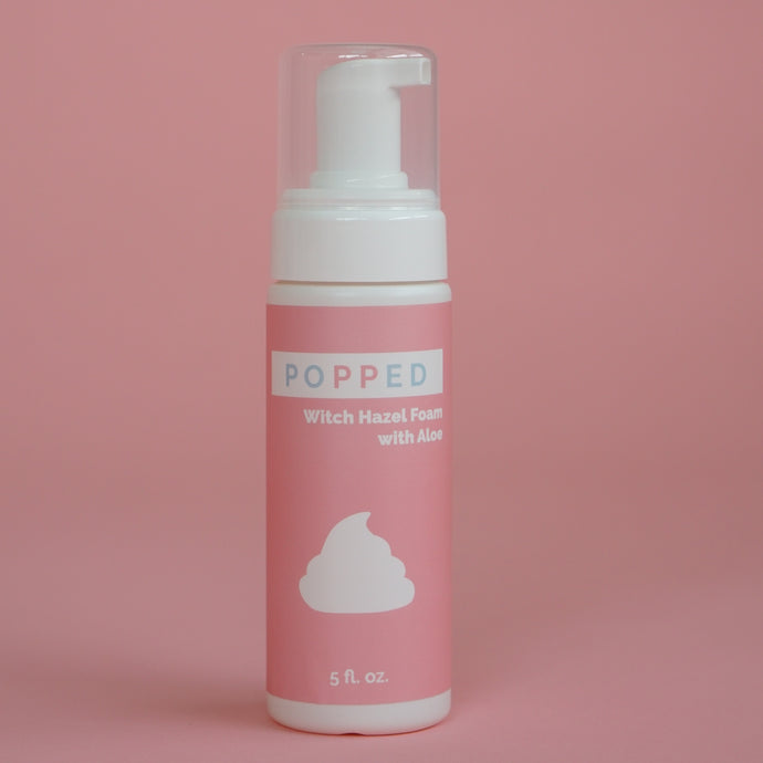 Tall white cylindrical bottle with pump/cap and a pink label reading: “Popped Witch Hazel Foam with Aloe, 5 fl oz.”  There is also an icon of the foam on the label.